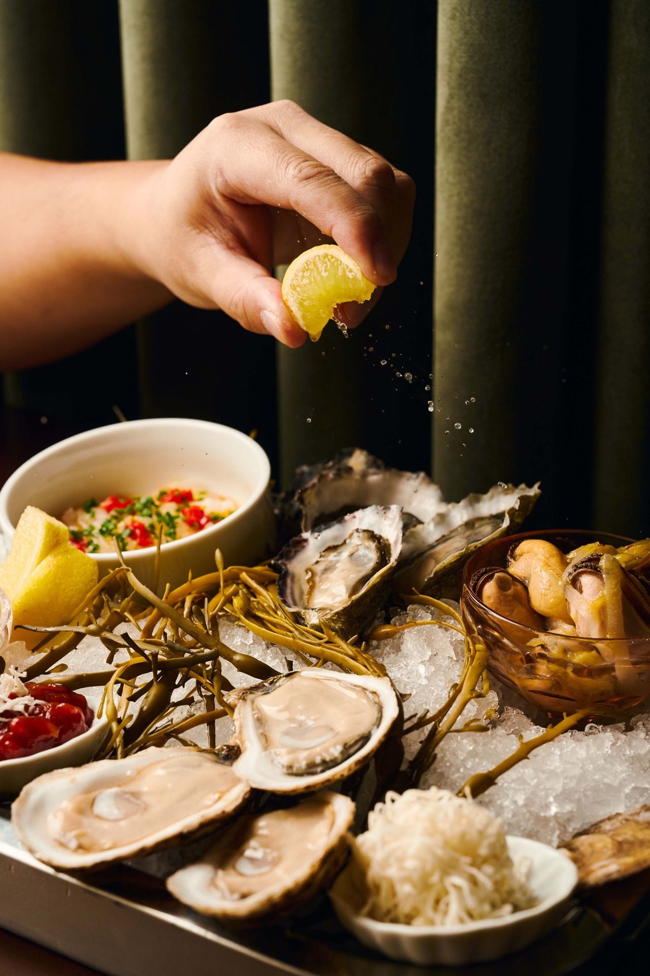 A person squeezes lemon over raw seafood