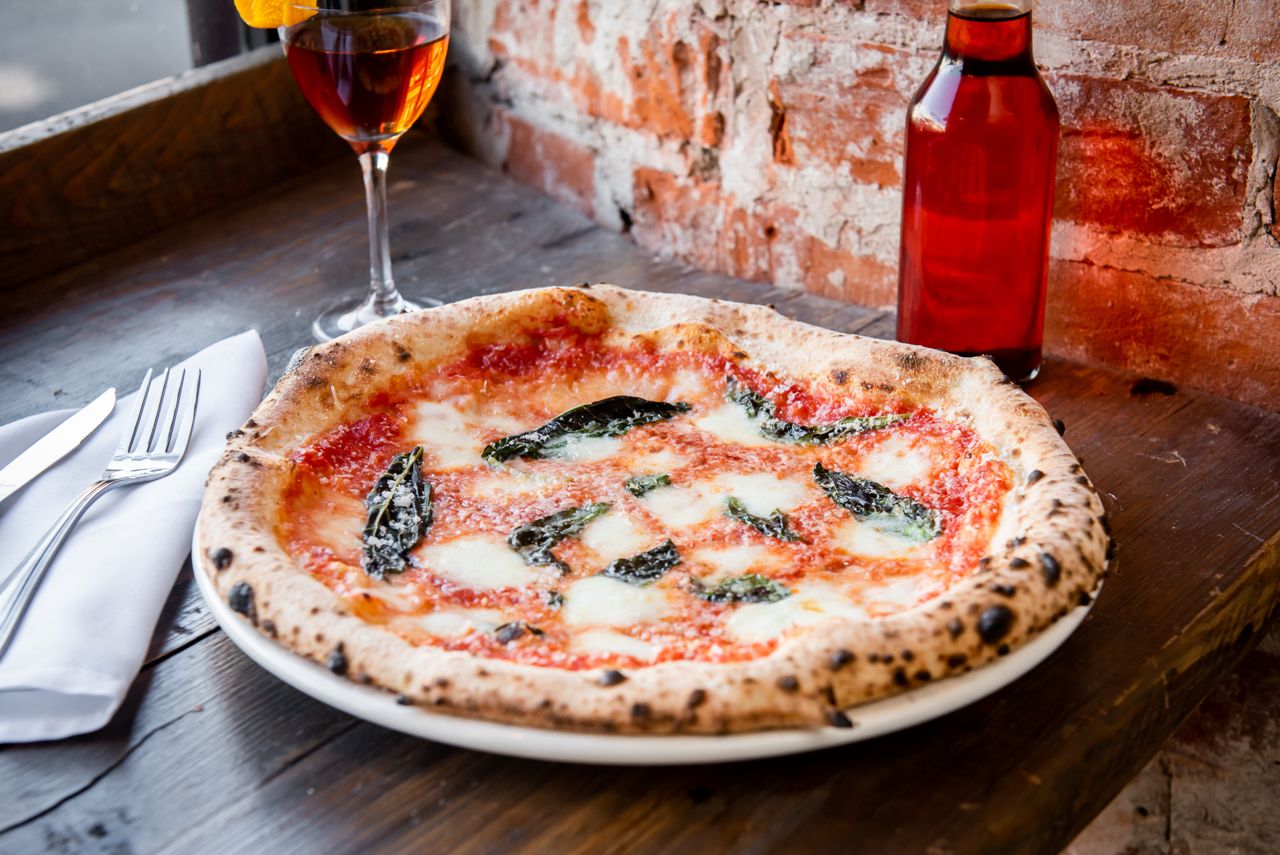 A pizza next to a glass of wine