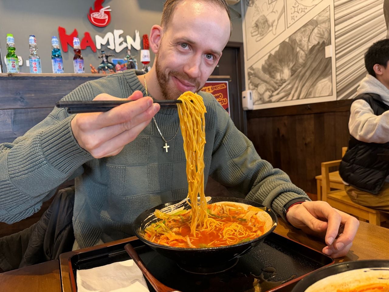 Chef Robert Balint uses chopsticks to pick up noodles from a bowl of ramen