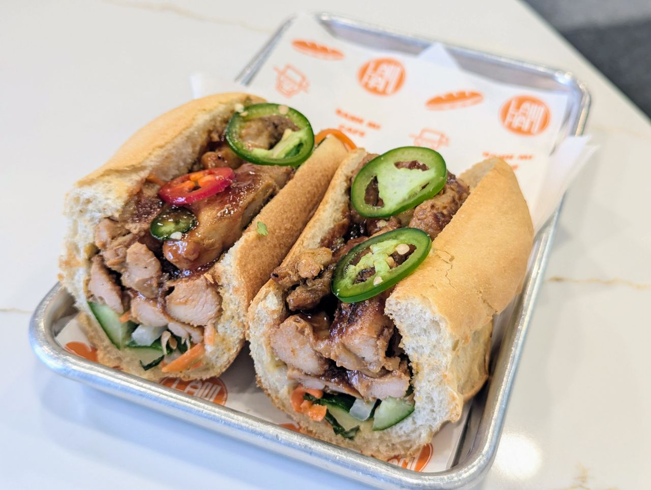 A closeup of a lemongrass chicken banh mi with jalapenos