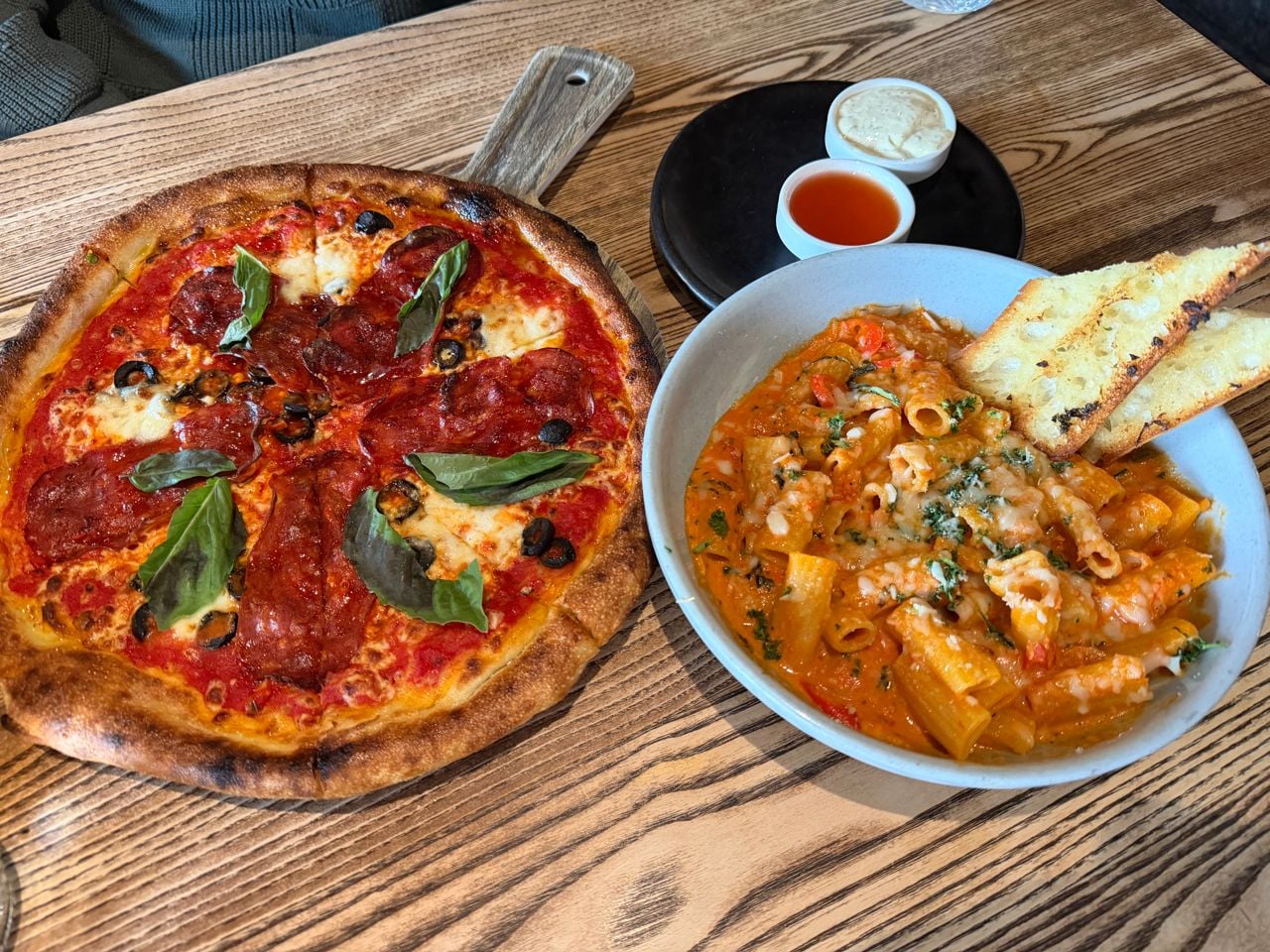 A pizza and a bowl of rigatoni alla vodka