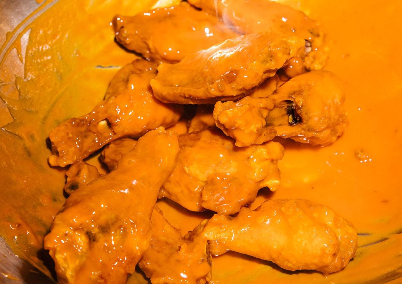 A closeup of saucy chicken wings in a bowl