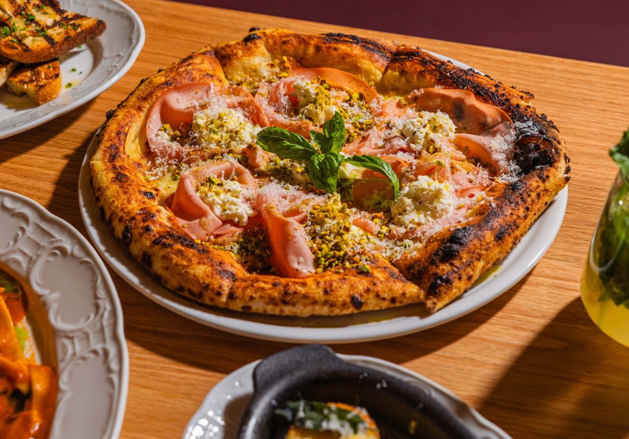 The mortadella e pistachio pizza is topped with shaved mortadella, fior di latte, crumbled pistachios, stracciatella and grana padano, then cooked in wood-fired pizza oven for that classic charred and smoky Neapolitan-style pizza taste