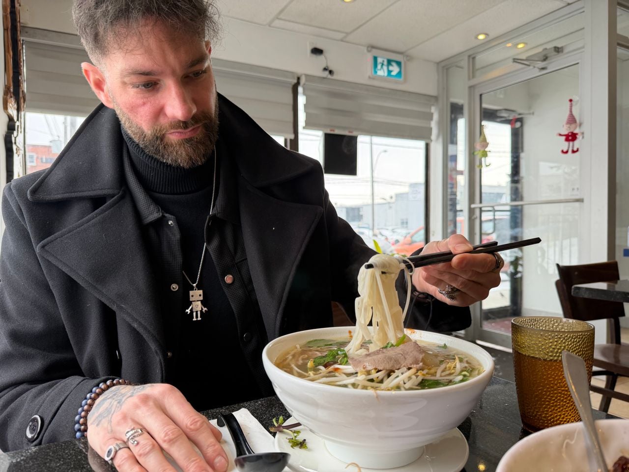 Chef Romain Avril uses chopsticks to pick up noodles from a bowl of pho