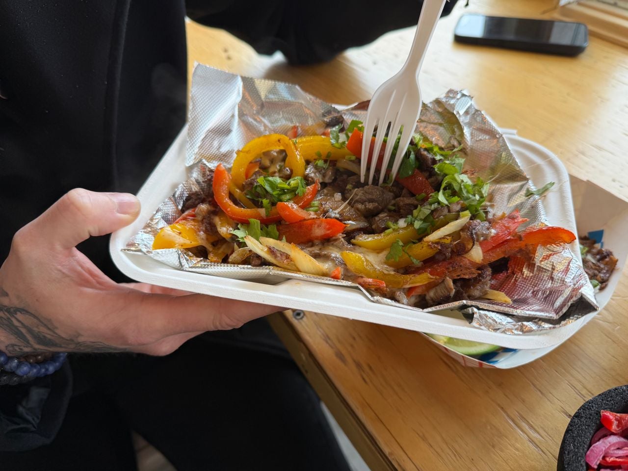 A person uses a fork to eat an order of alambre at Tacos Casa Sonora in Toronto