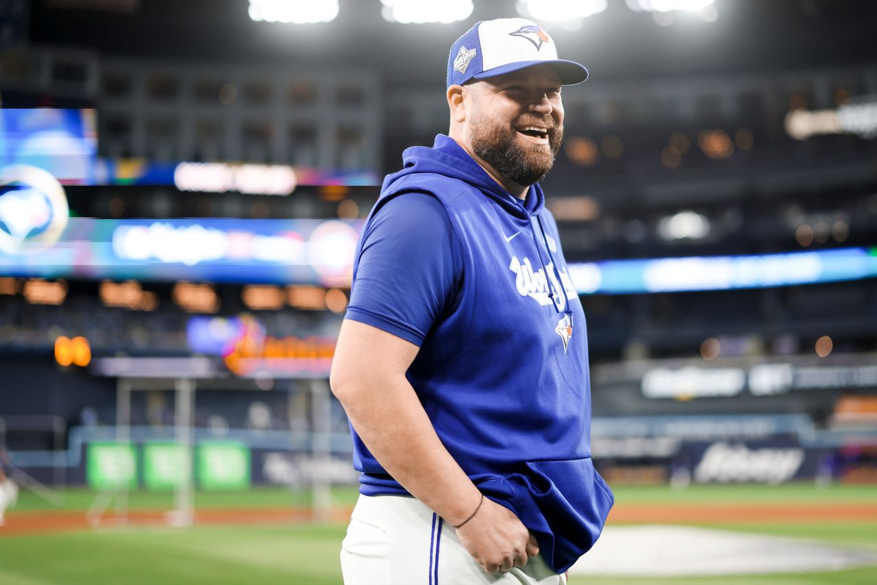 Blue Jays manager John Schneider smiles on the pitch of the Rogers Centre.