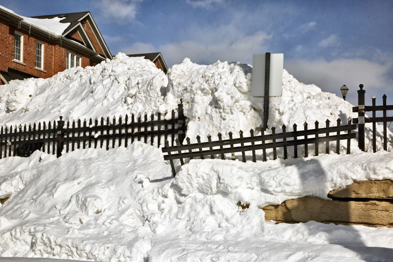 A fence that a snowplow broke is covered in snow.