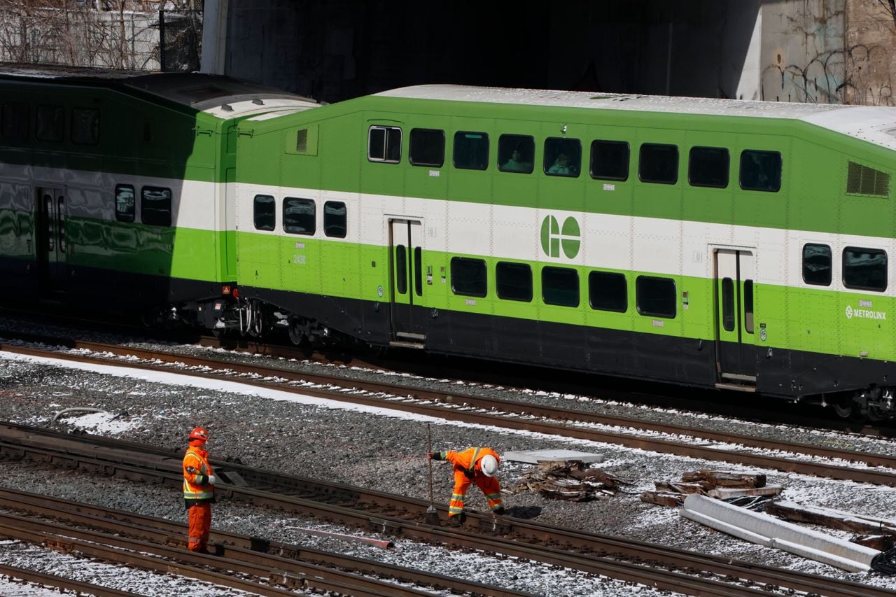 People wearing high-visibility clothing work along the tracks near Bathurst Street and Front Street West in Toronto.