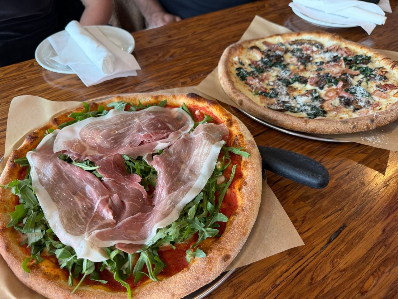 A closeup of a prosciutto pizza and a mushroom pizza