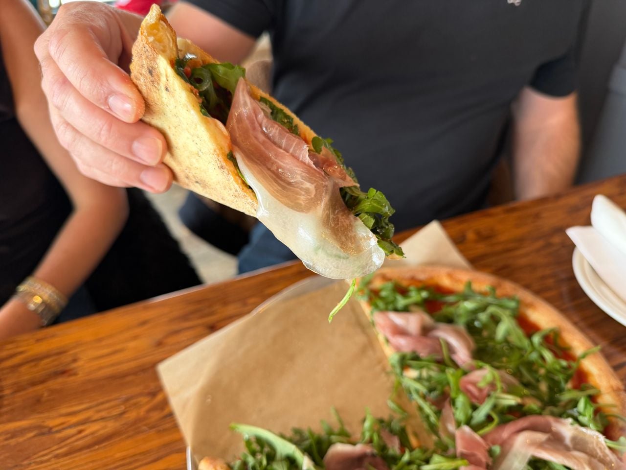 A closeup of a folded slice of pizza topped with prosciutto