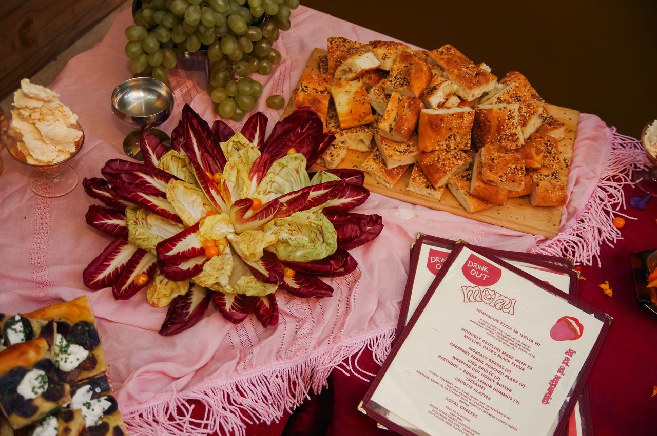 A spread of radicchio, bread, dips and grapes next to menus