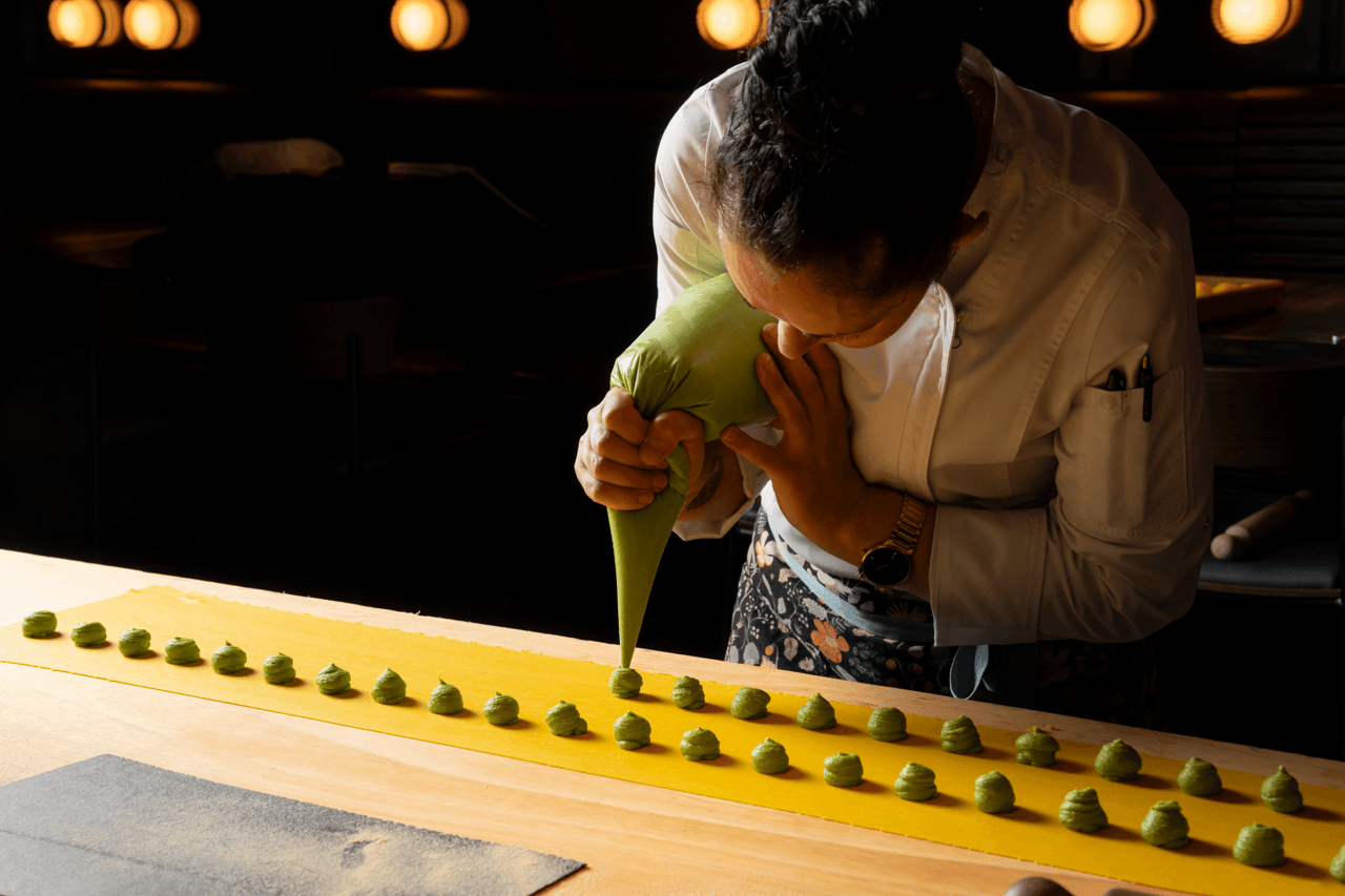 A chef pipes filling into sheets of pasta