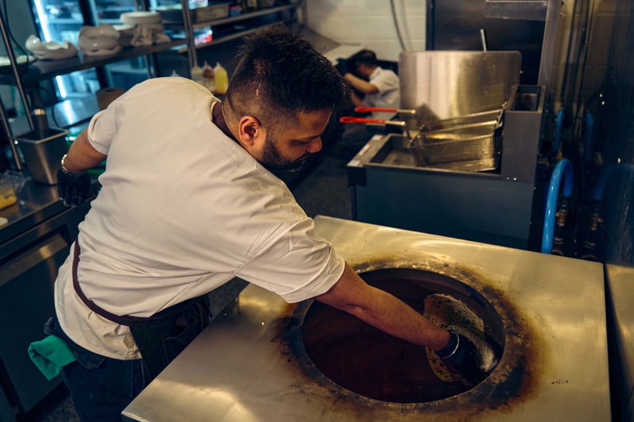 A chef places naan inside a tandoor