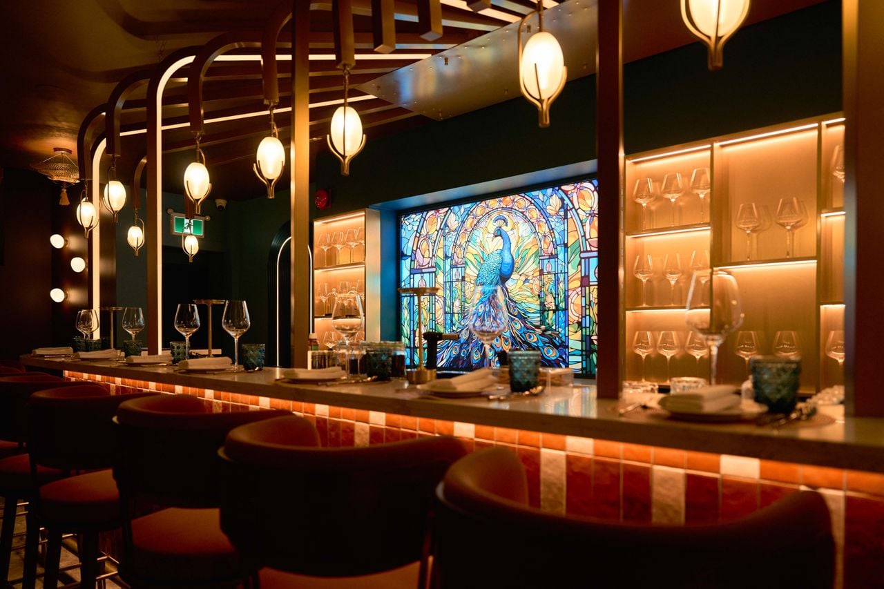 The bar at Aangan, with a stained-glass peacock behind it