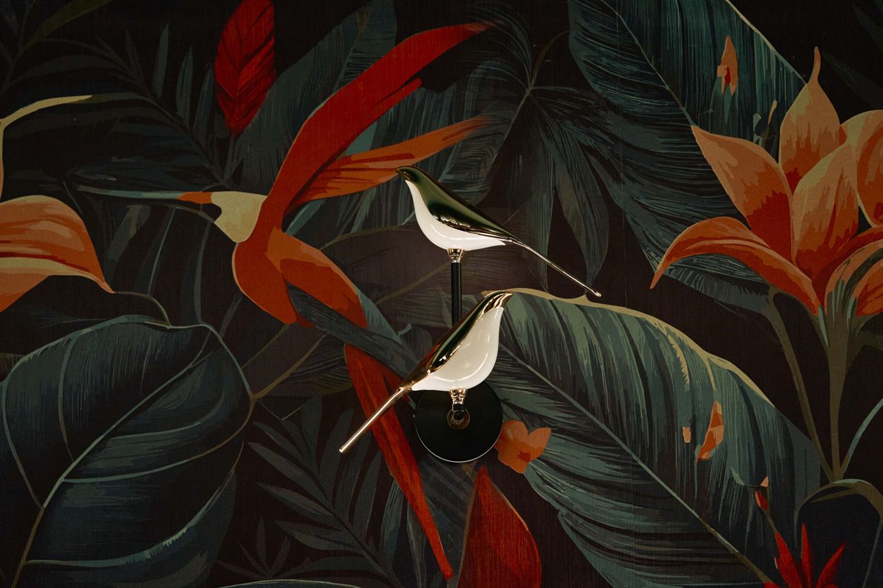 A closeup of the jungle-themed wallpaper and bird-shaped light fixtures at Aangan