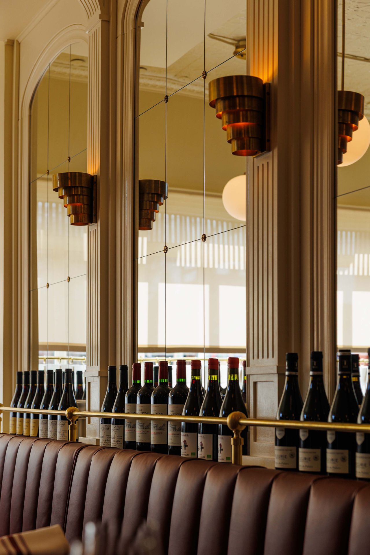 Bottles of wine behind banquette seating in the dining room of Brasserie Côte