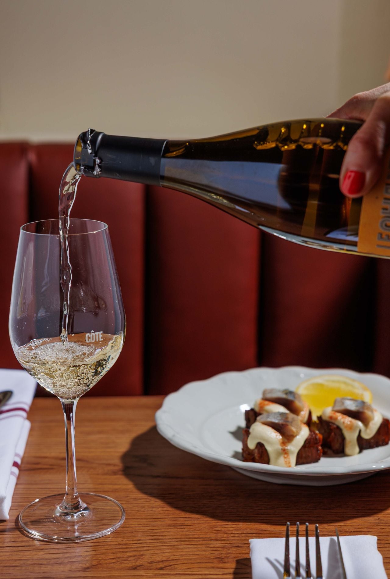 A person pours a glass of white wine