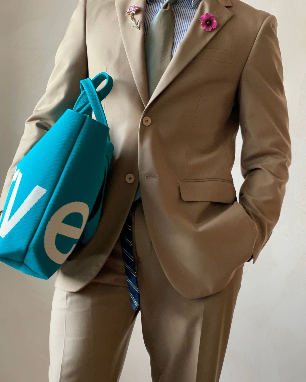 Man in brown suit carrying turquiose bag