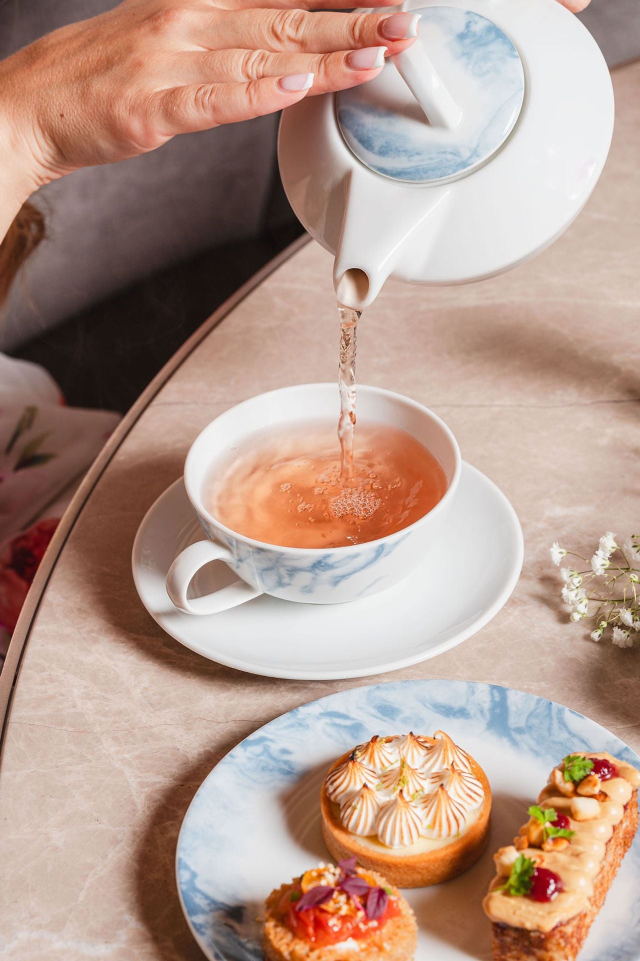 A person pours tea from teapot into a cup