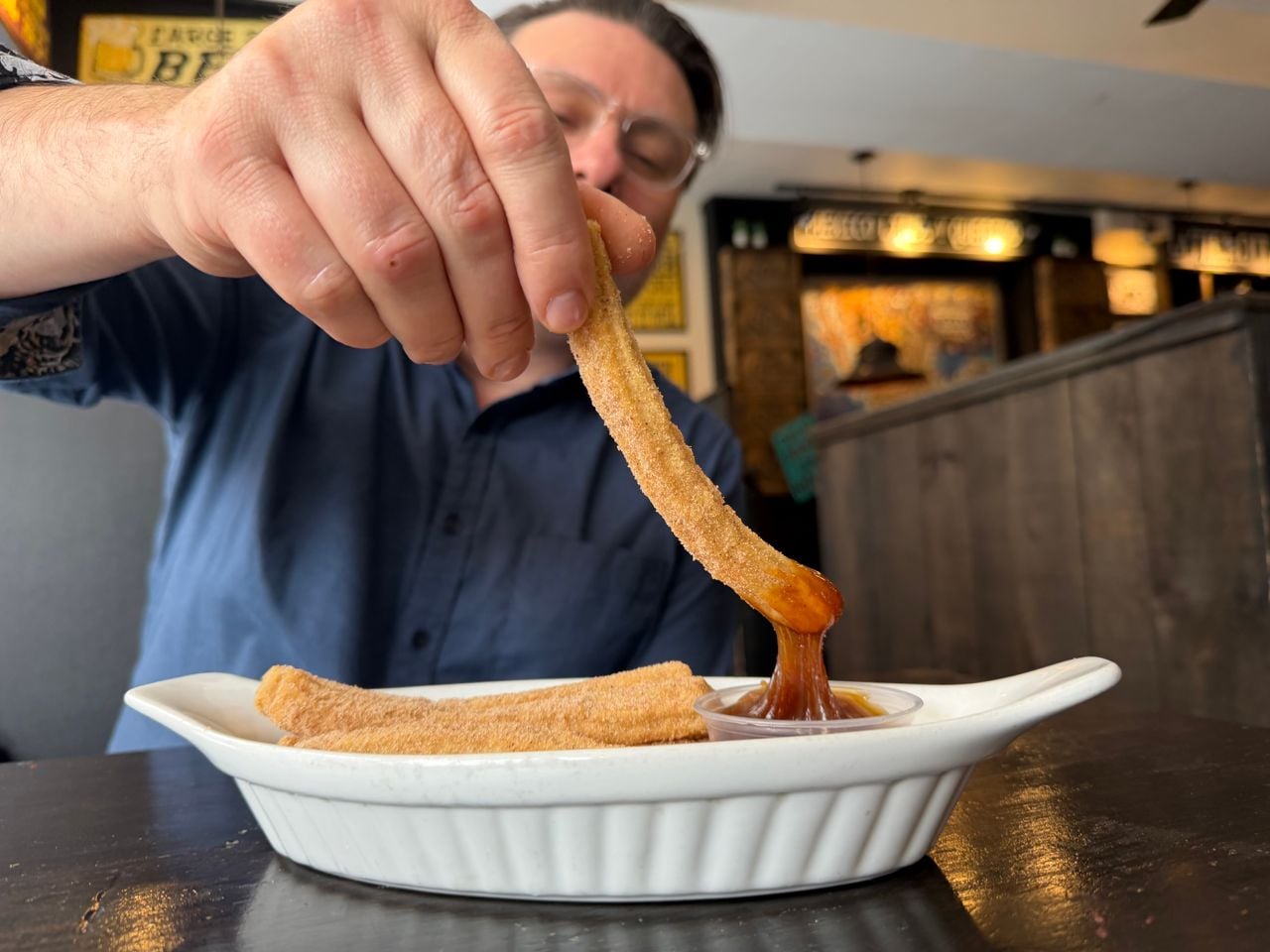 Riley Krieger-Mercer dips a churro in caramel sauce