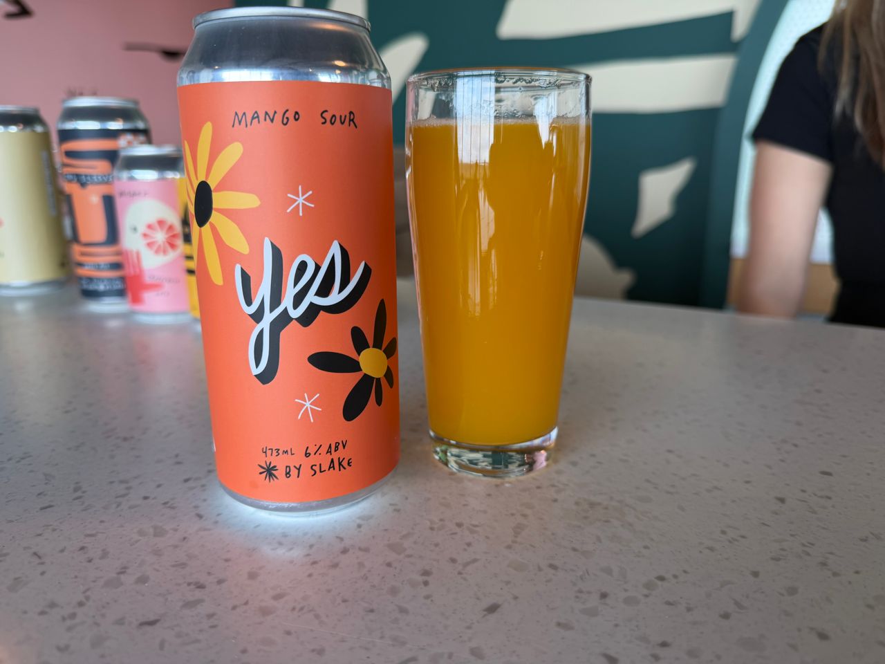 A can of Slake's mango sour next to a glass of beer