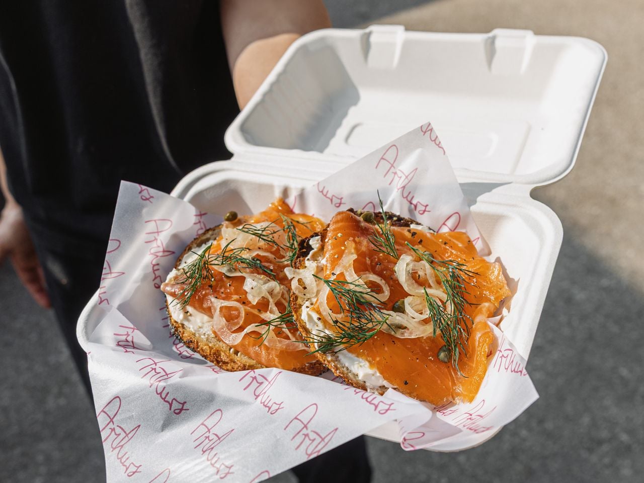 A closeup of a bagel topped with cream cheese, smoked salmon, capers, onions and dill