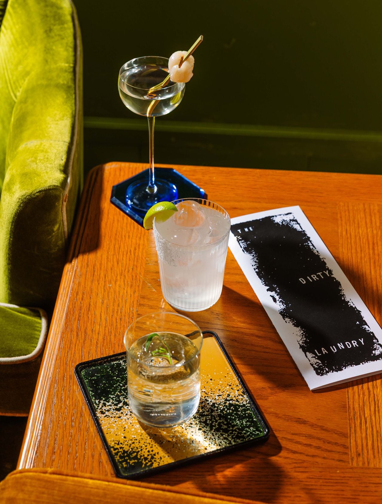 Three cocktails on a table next to a menu at the Dirty Laundry