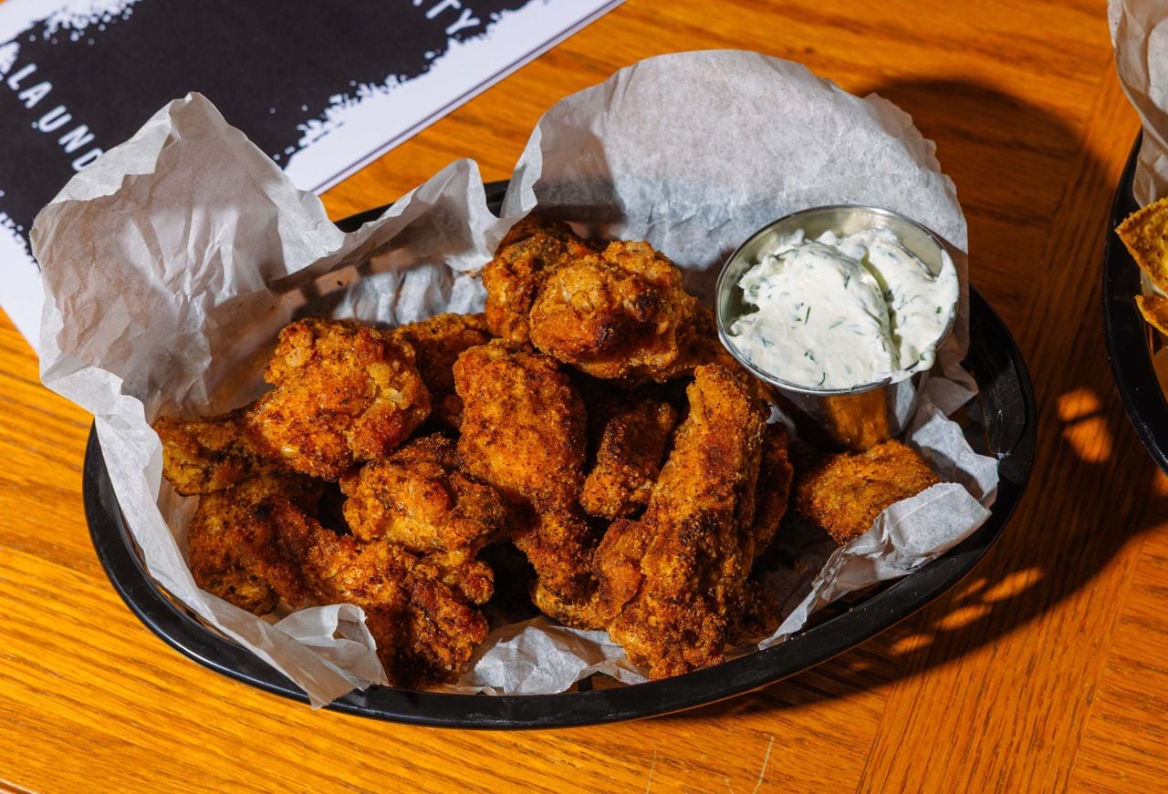 A basket of chicken wings with a container of dip
