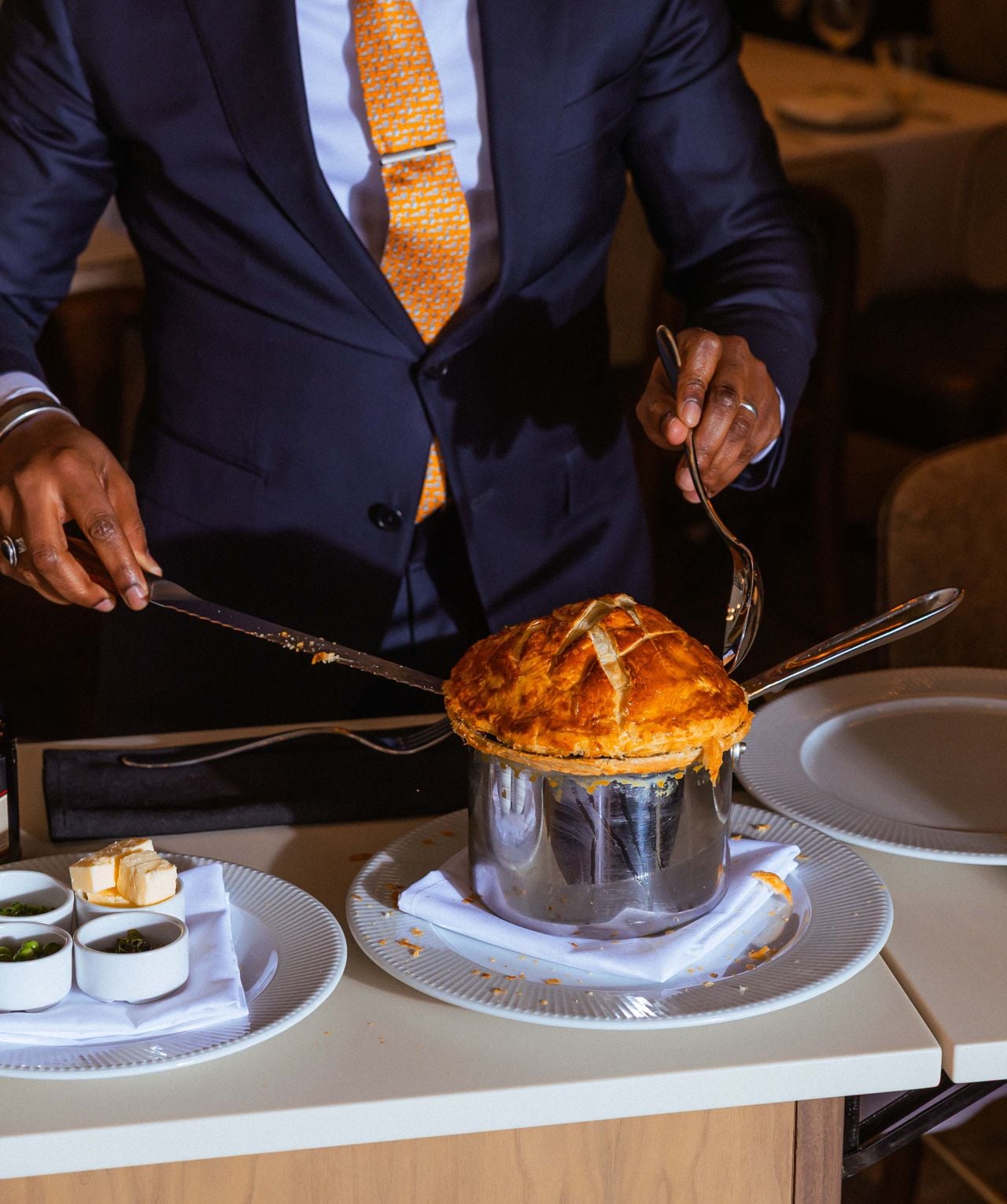 A server cuts open the pastry shell of a lobster pot pie