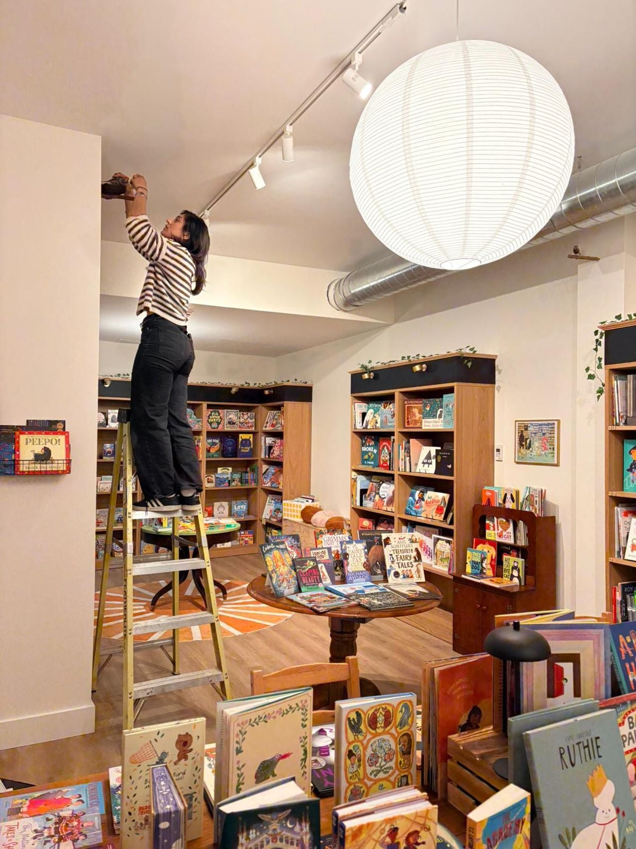 Woman standing on a ladder, shelving a book
