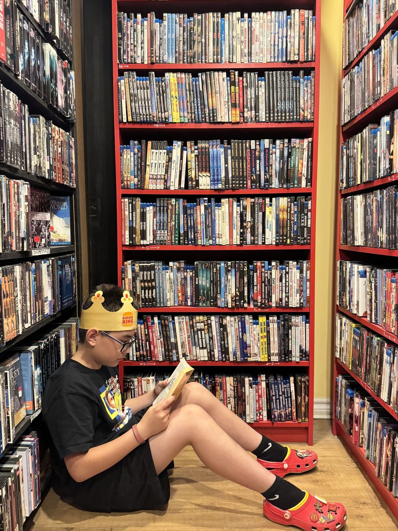 Kid sitting in front of DVD racks