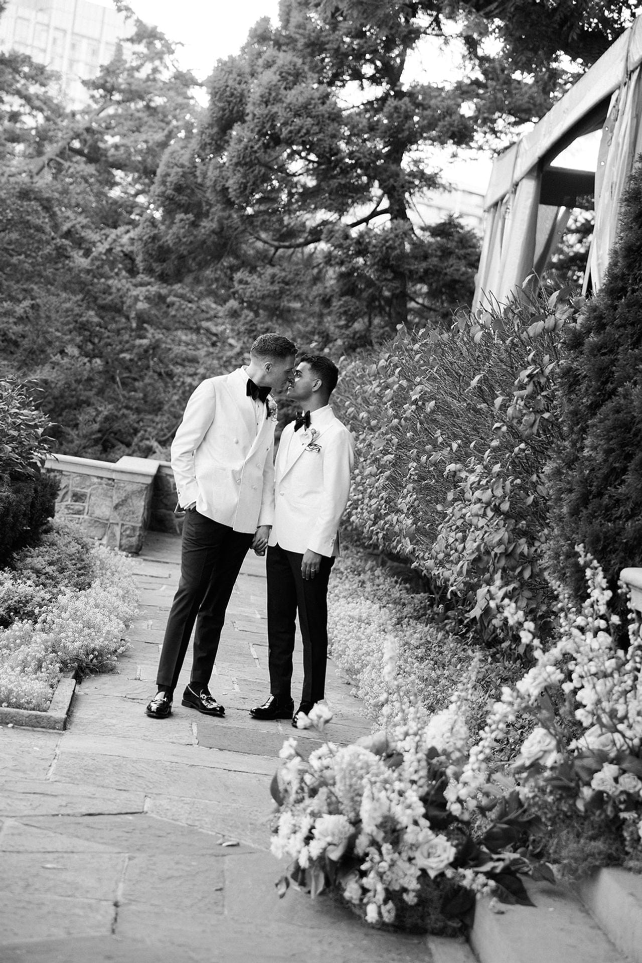 Two grooms in white jackets kissing