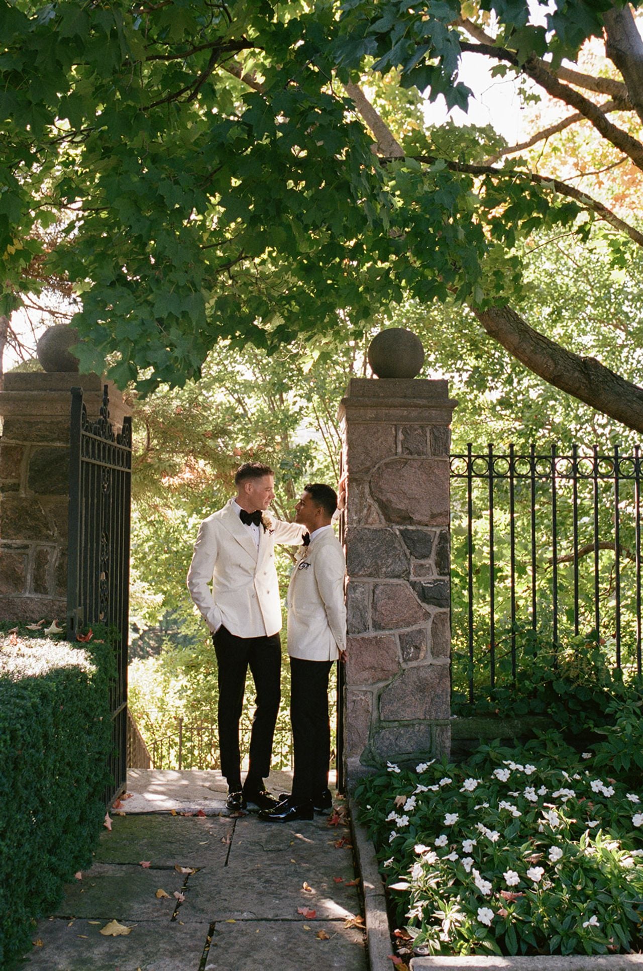 Two grooms standing in a garden