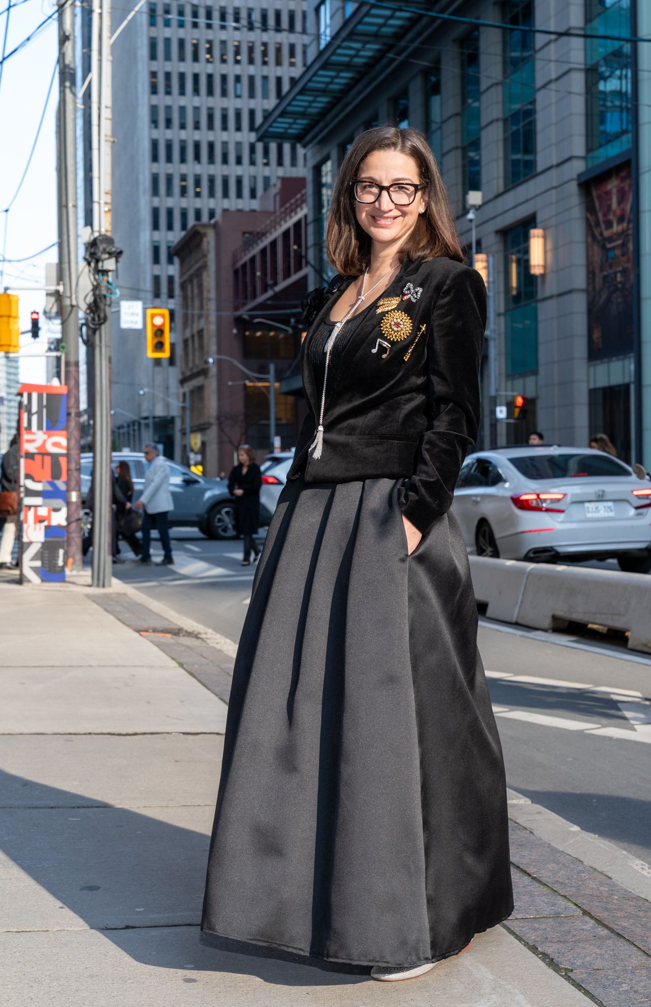 Woman wearing black velvet jacket with brooches and black taffeta skirt