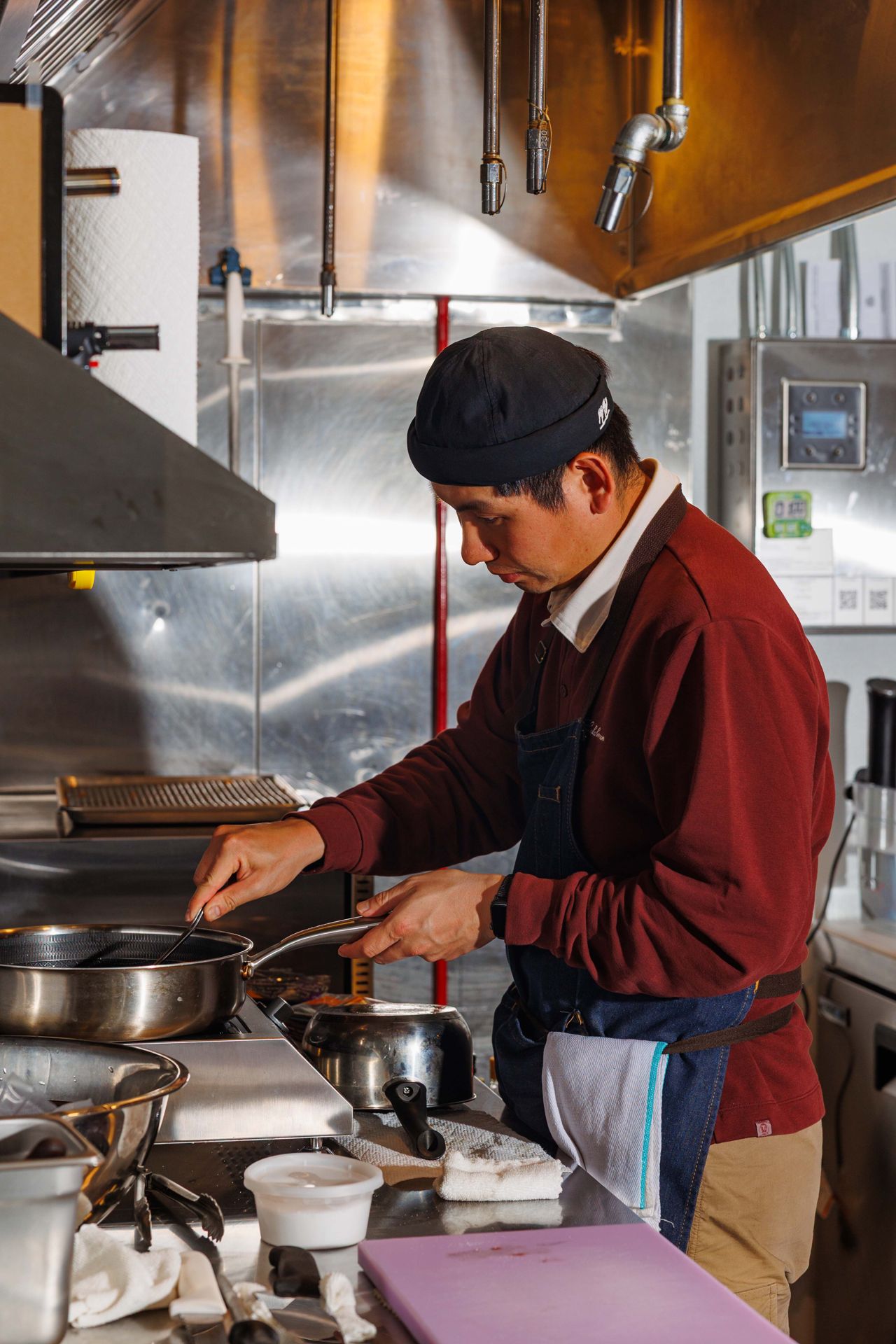 A chef stirs something in a pot on a stove