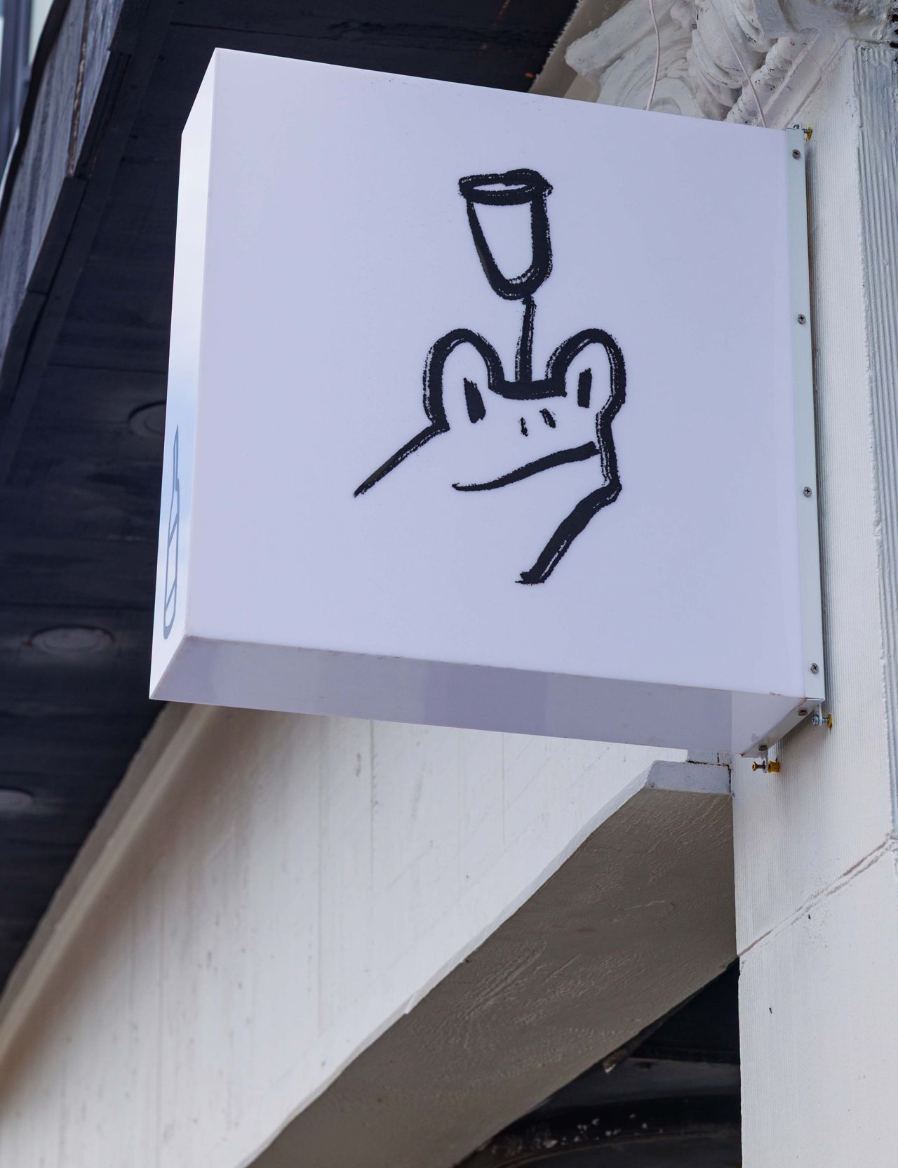 A sign with a cartoon frog and a wine glass