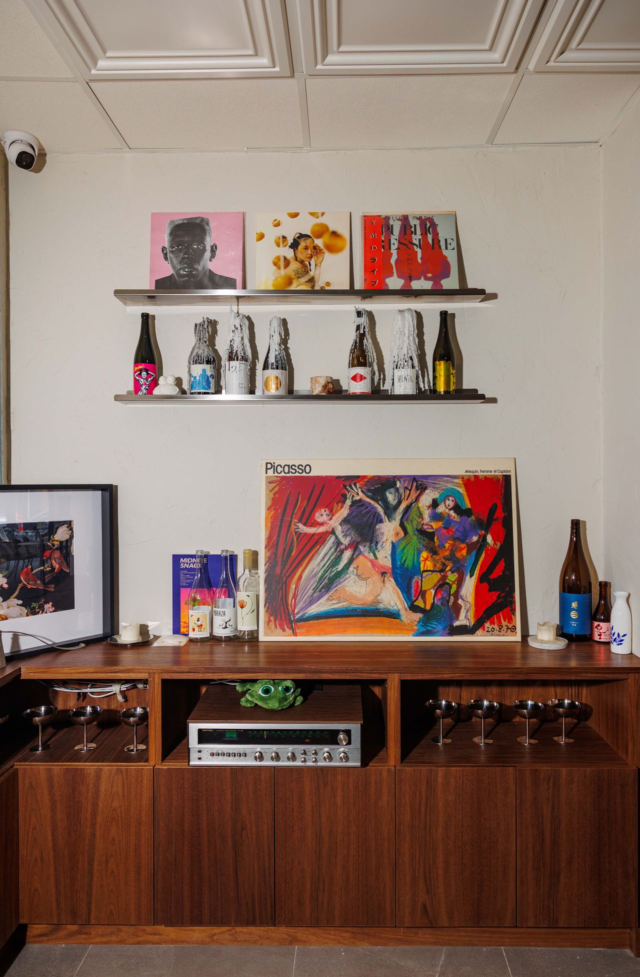 A display case with an audio system, wine bottles, record and glasses