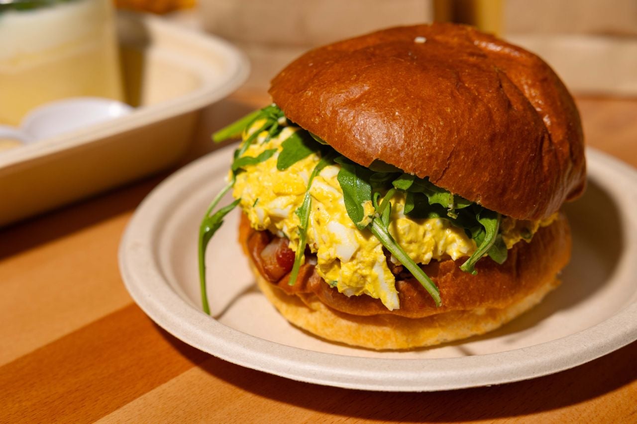 An egg salad sandwich with arugula and bacon