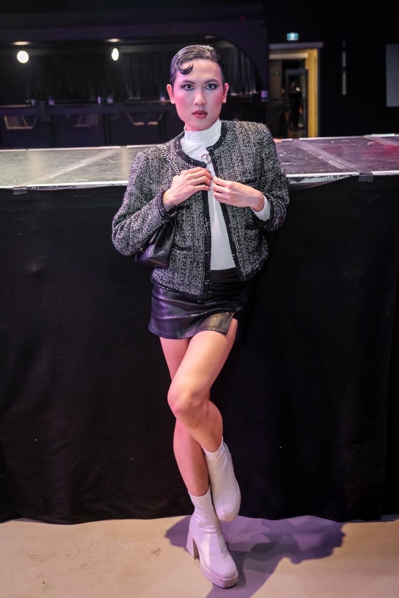 A performer in a tweed cropped jacket and leather mini skirt