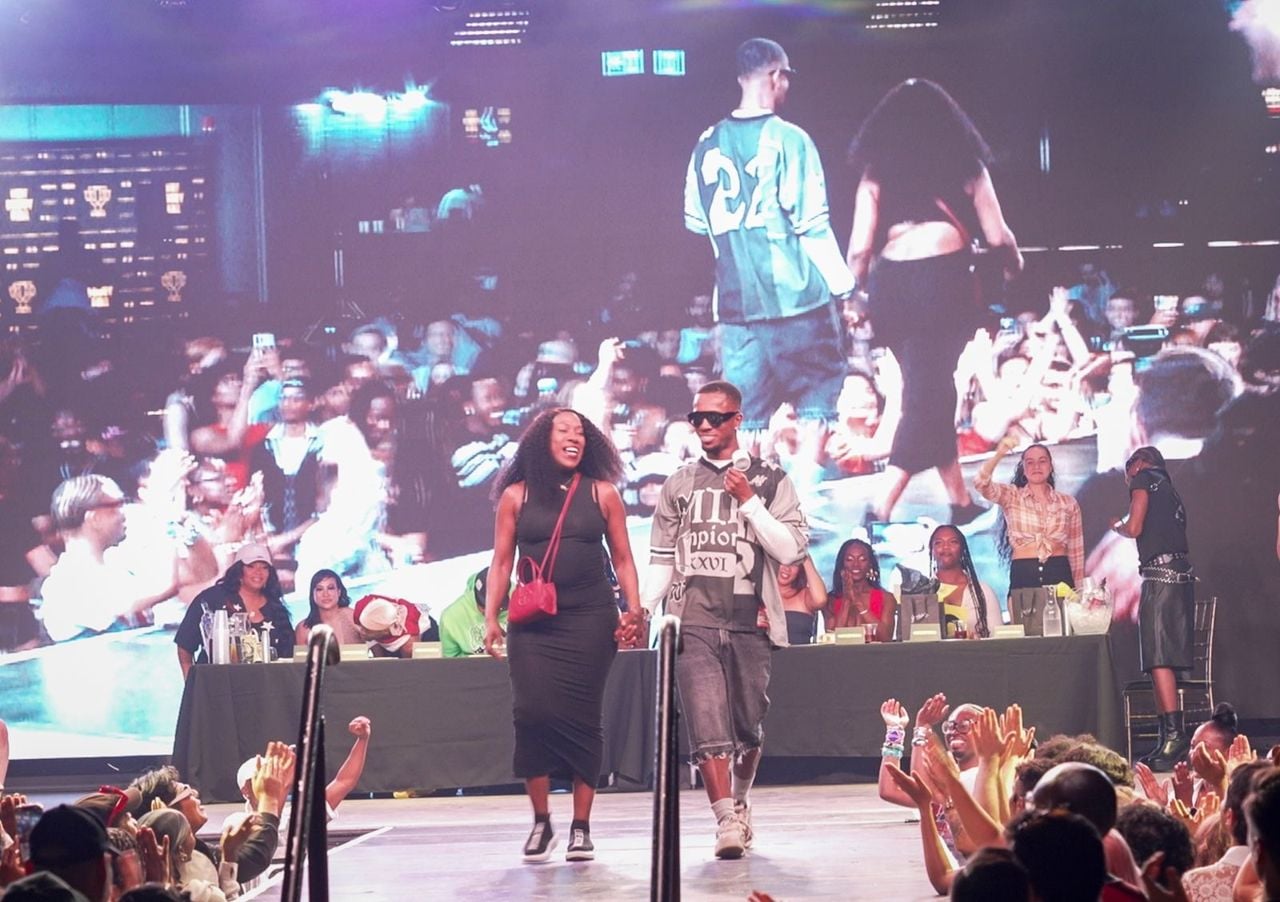 Two performers walking down the runway in front of a crowd at the Hot Body Ball