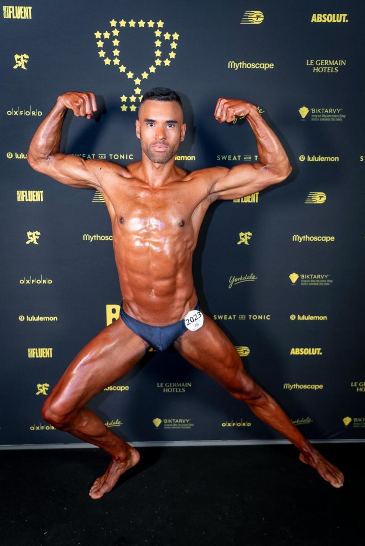 A performer in a blue speedo posing flexing in a bodybuilding pose