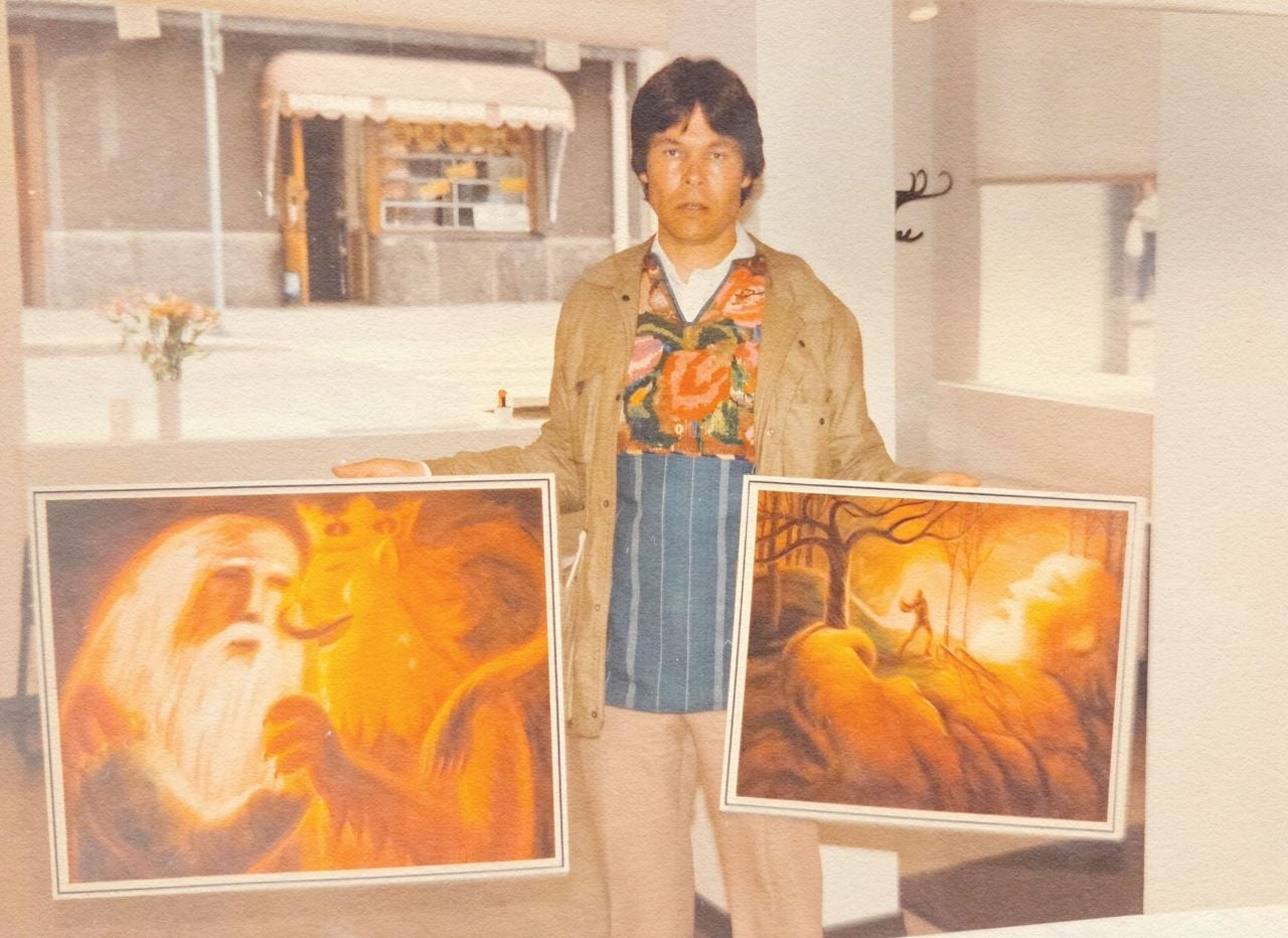 Artist Sami Suomalainen with two of his fantastical paintings