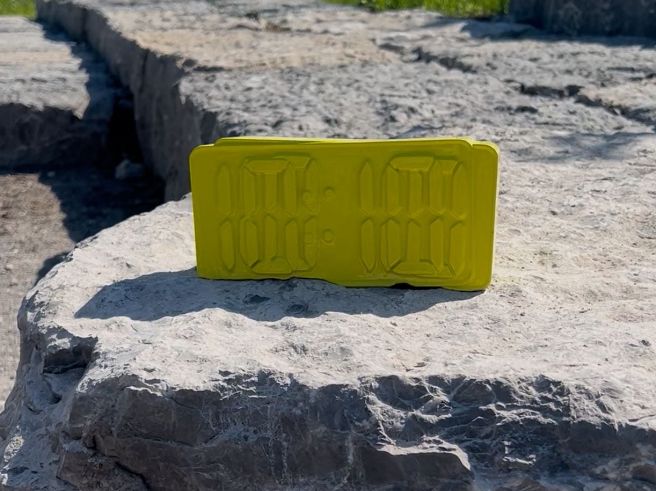 Yellow alarm clock sitting on a rock