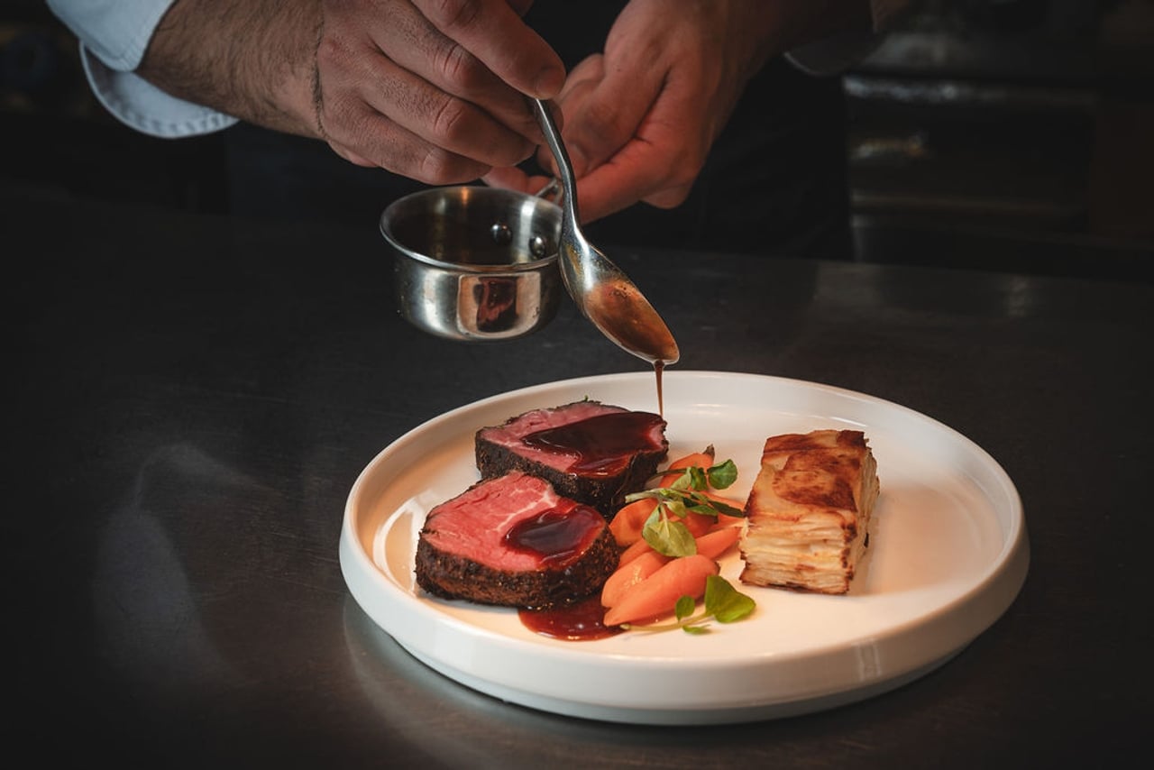 A server pours jus over a steak at Louix Louis