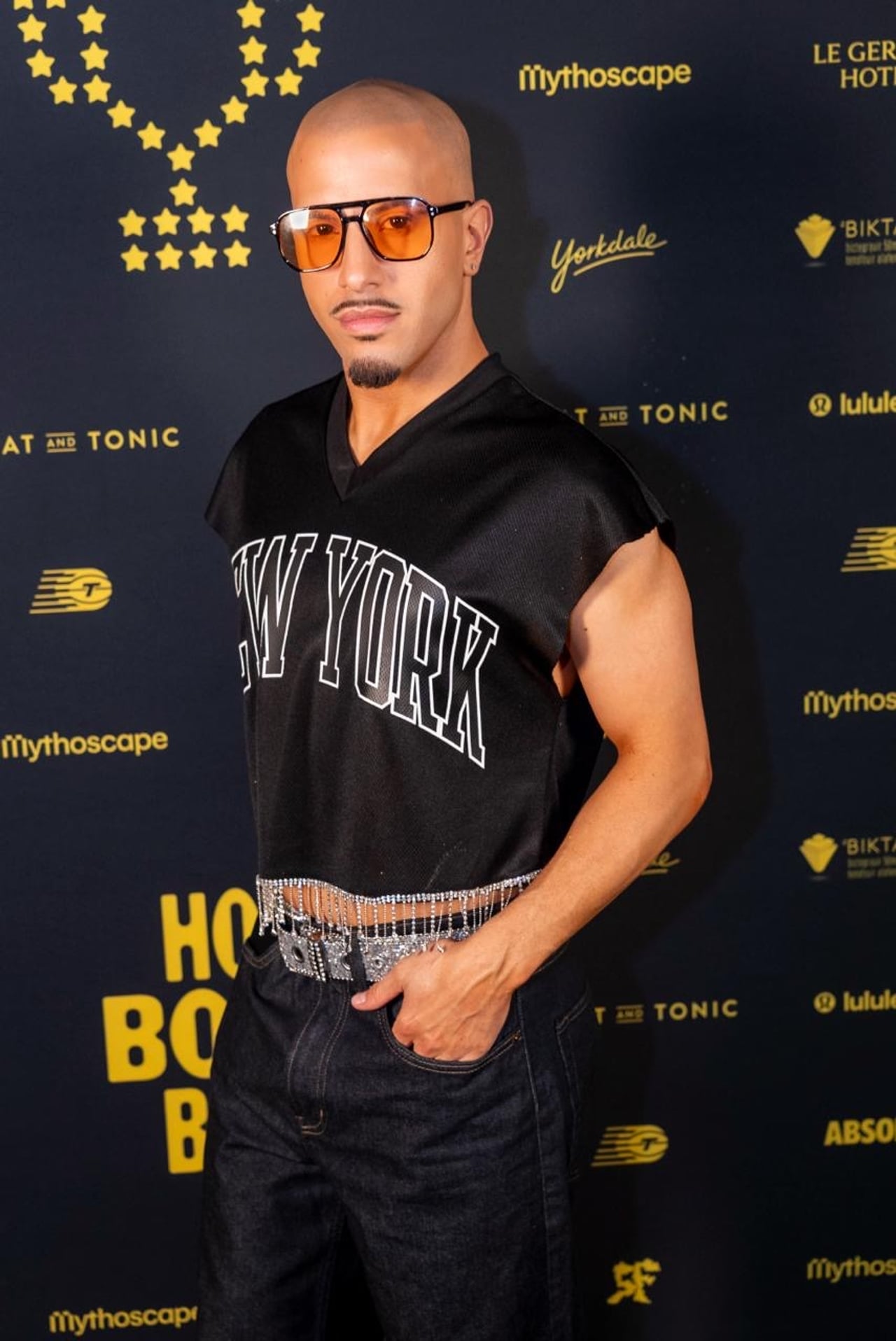 A performer with orange sunglasses and a cropped New York jersey hemmed with metallic fringe