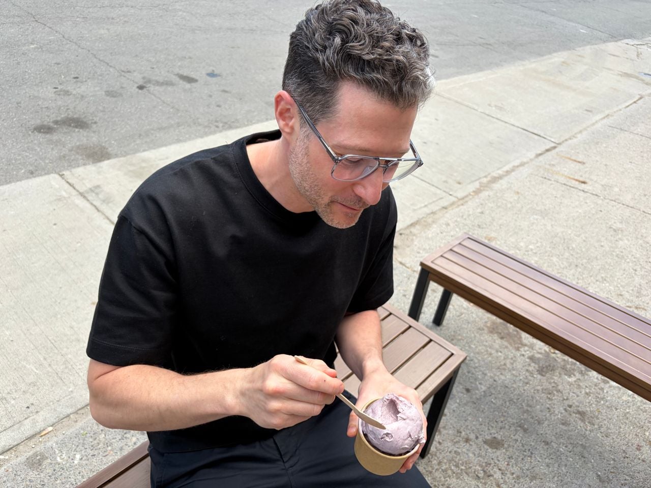 Adam Minster eats ice cream on a bench