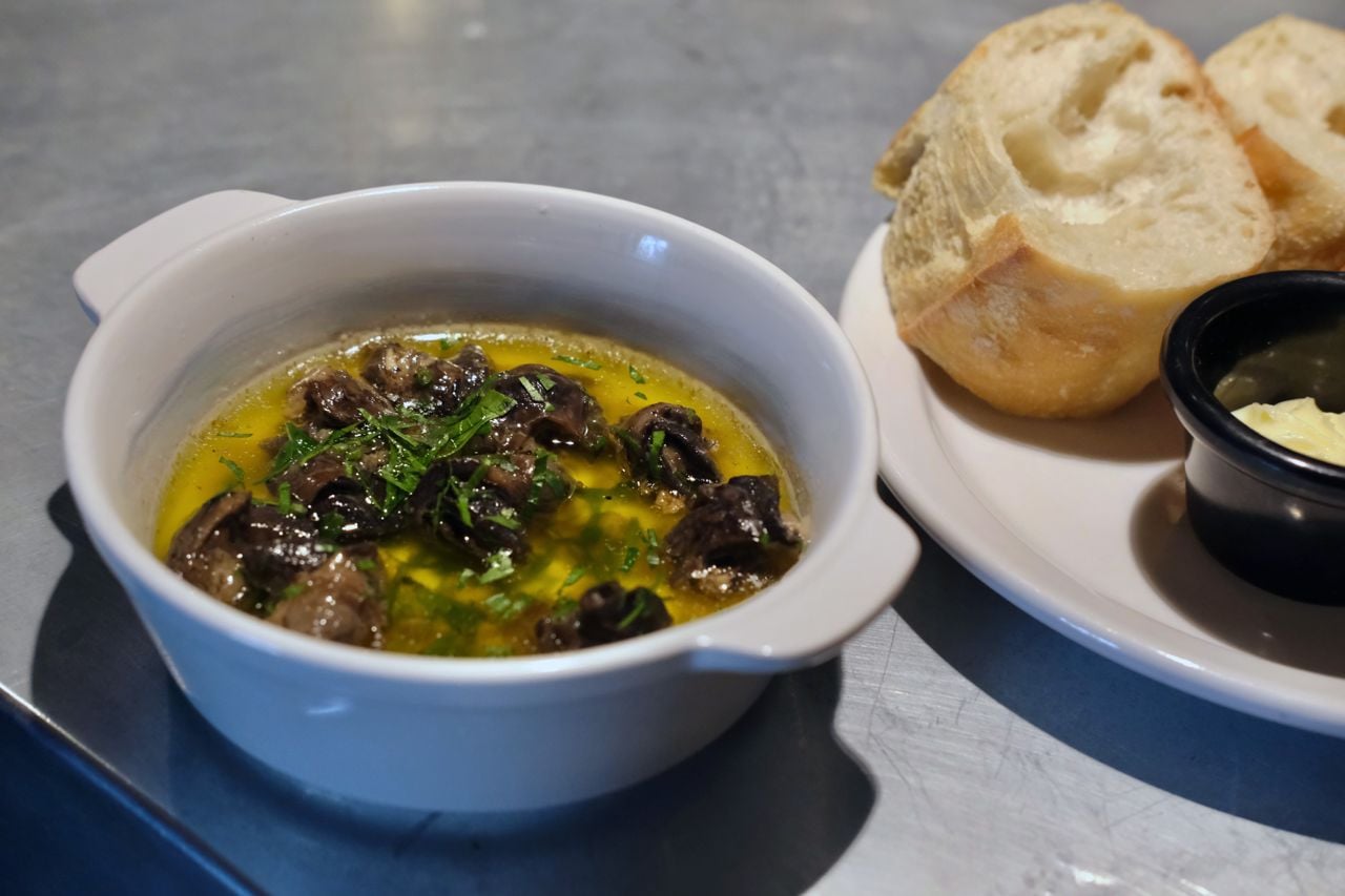 A bowl of escargot with bread on the side