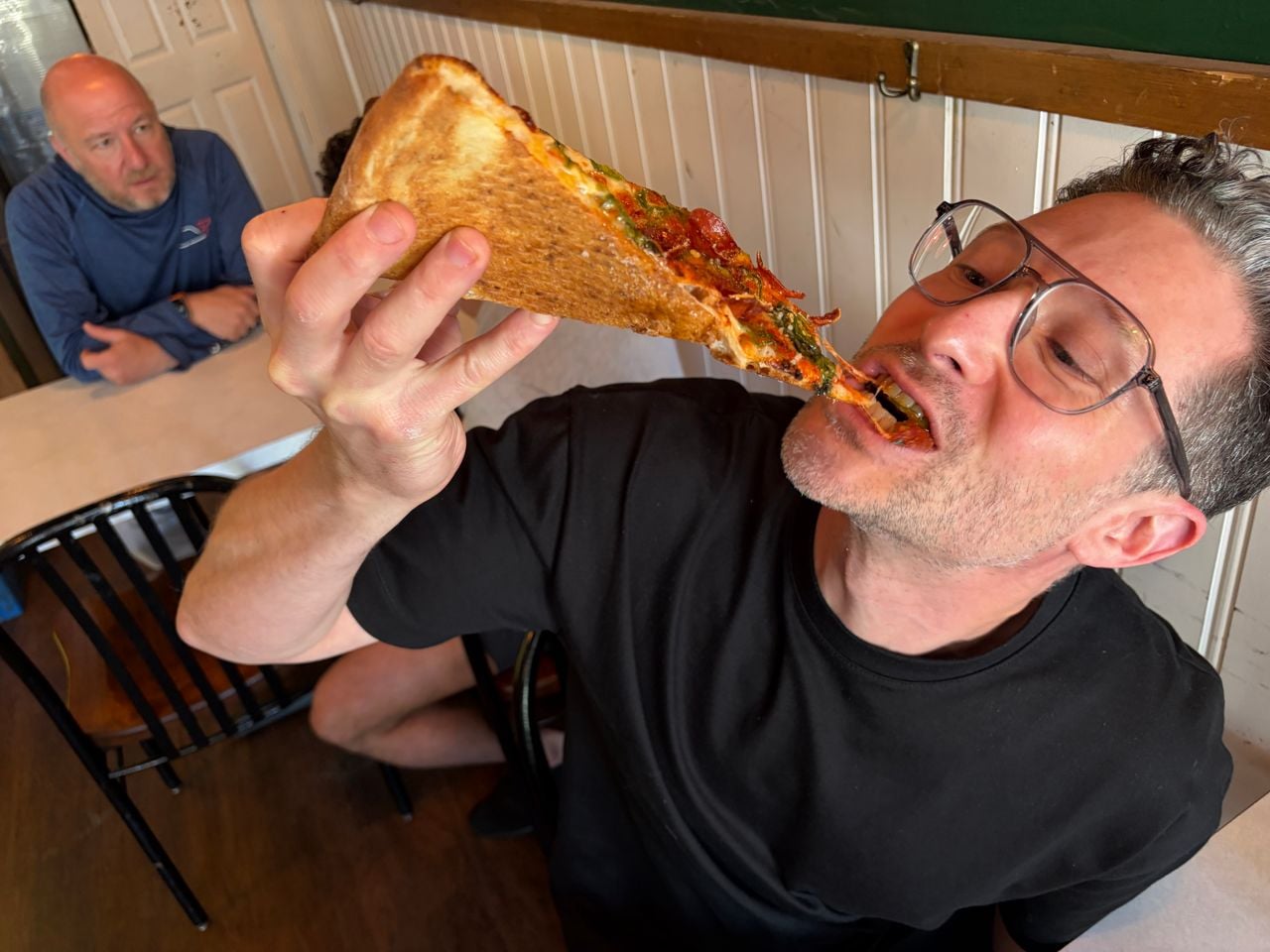 Adam Minster eats a slice of pepperoni pizza at Mac's Pizza