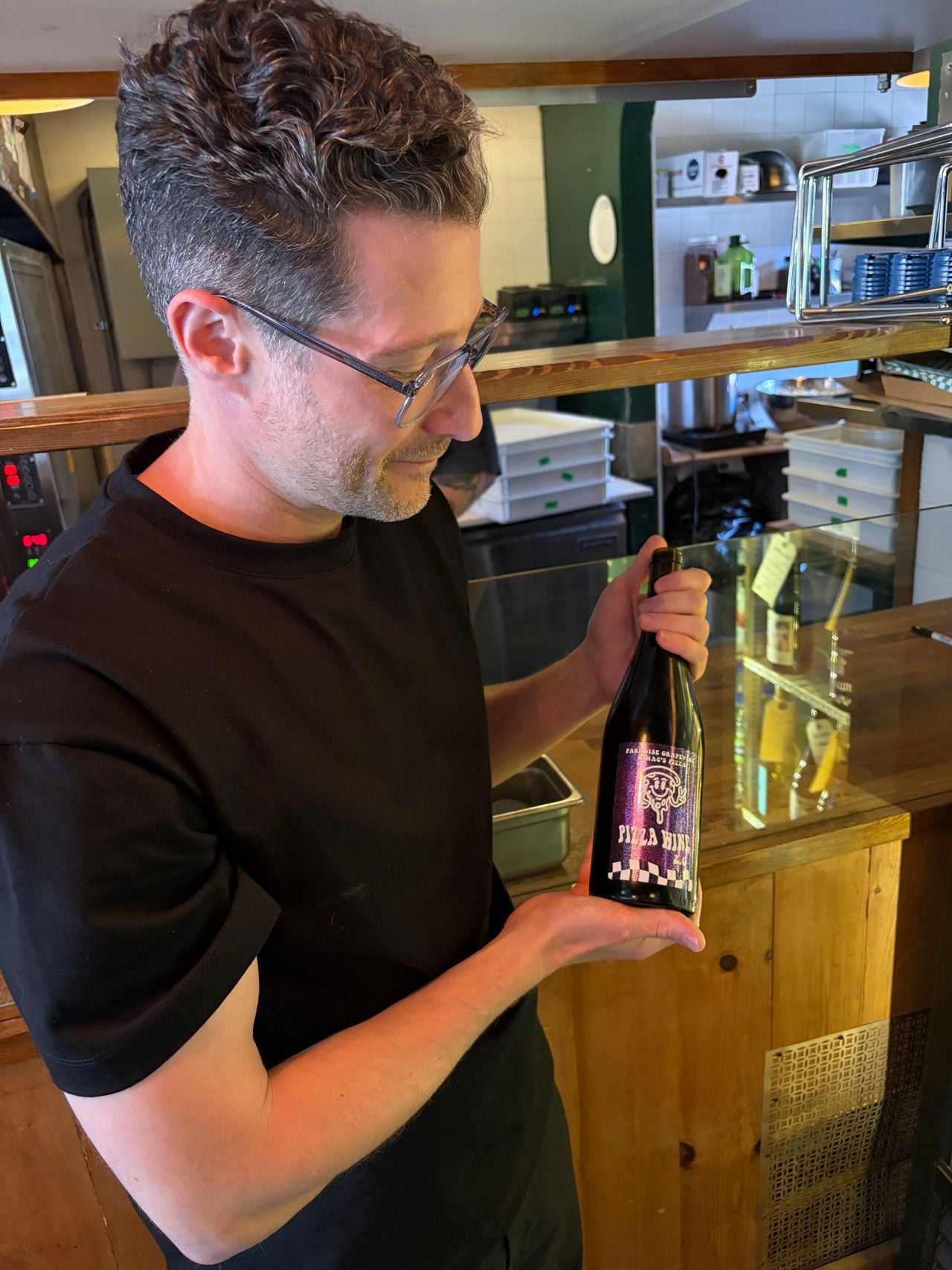 Adam Minster holds a bottle of Pizza Wine from Paradise Grapevine