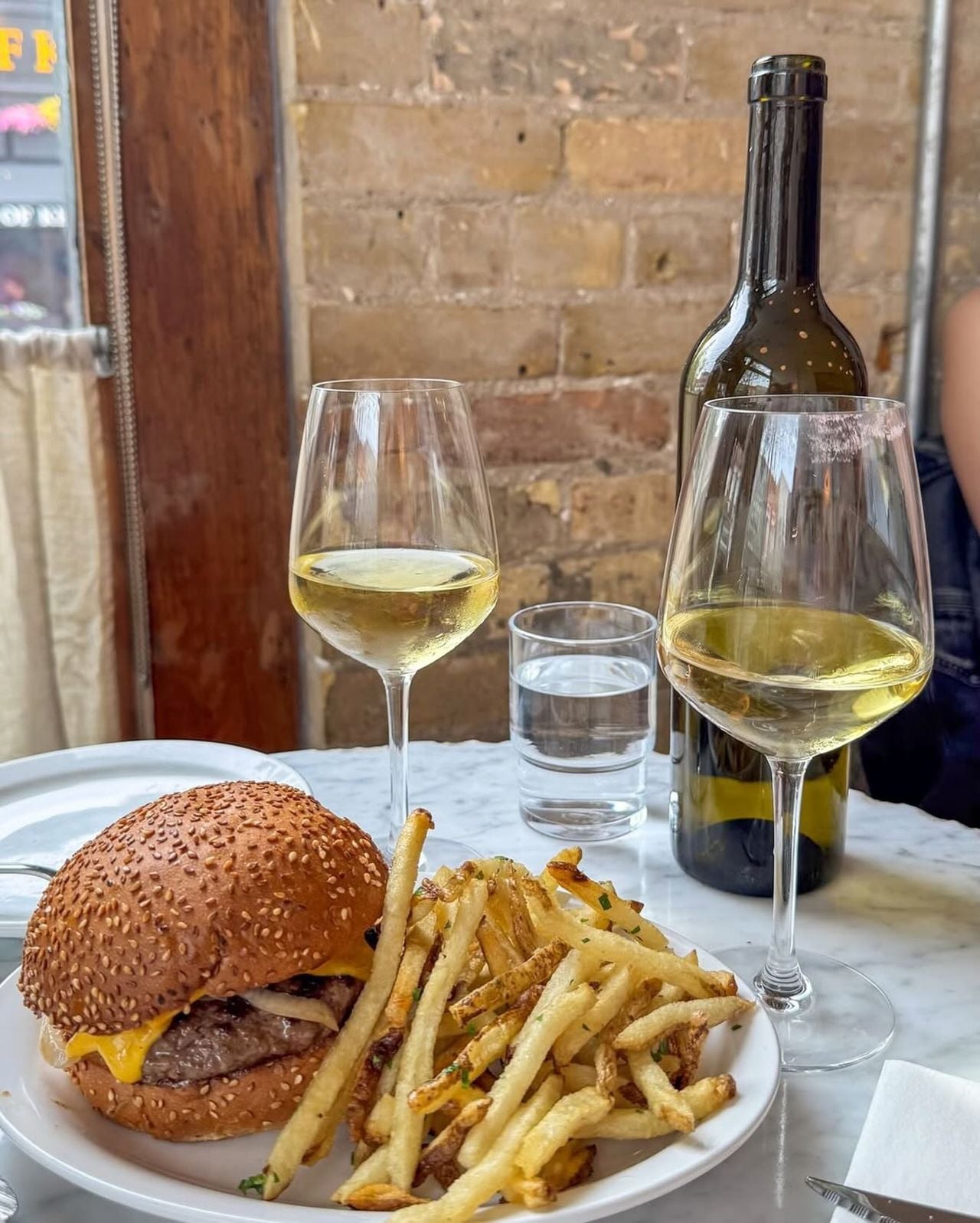 A burger with fries and white wine at Manita